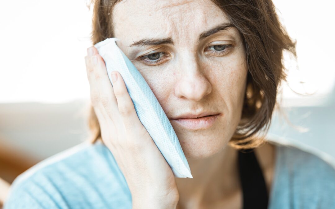 woman with an ice pack she is holding against her cheek