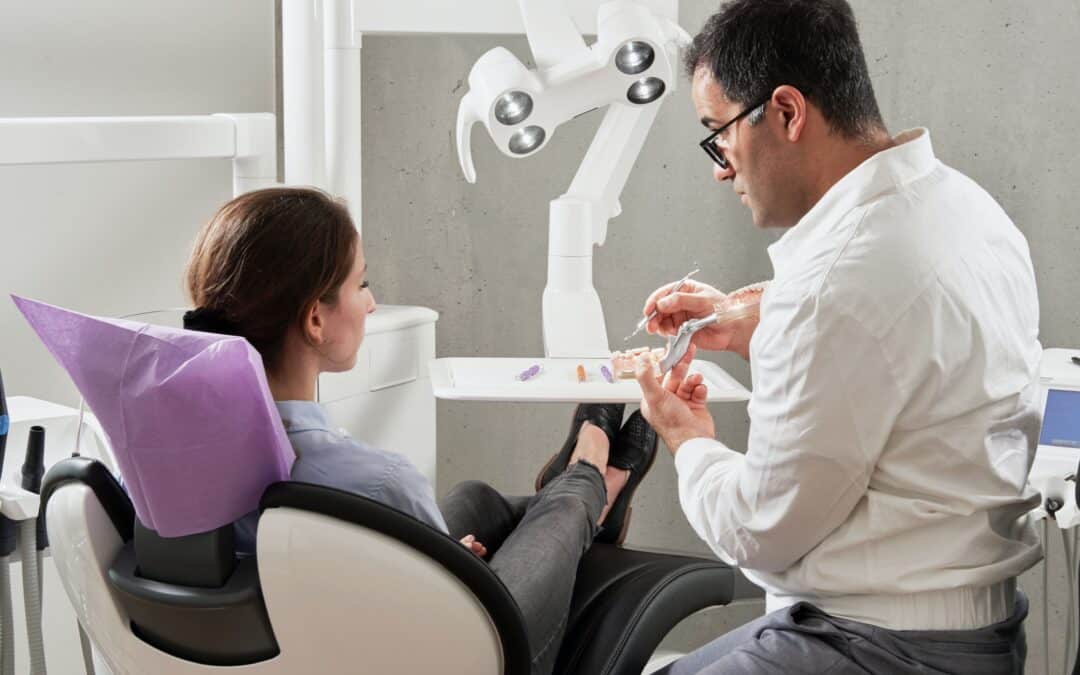 A dentist speaking with a patient in an examination chair
